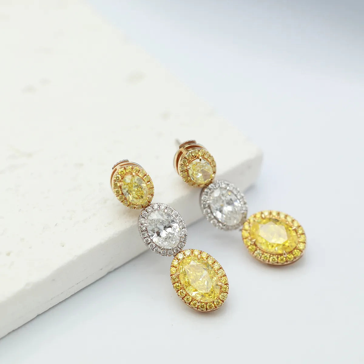 4.4 Carat Oval Cut Halo Three Stone Fancy Yellow Lab Grown Diamond Drop Earrings.