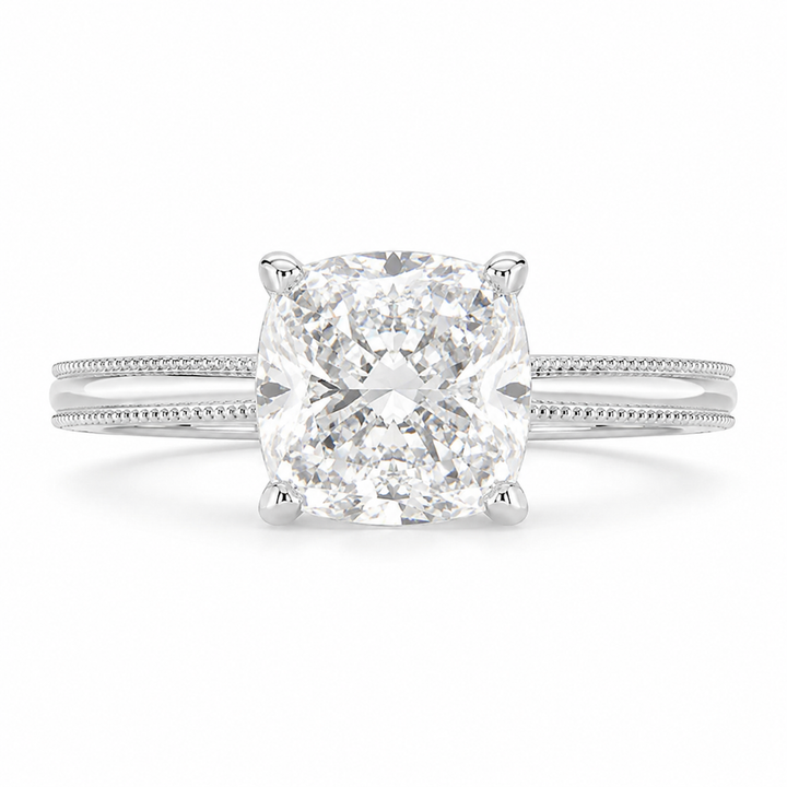 A radiant cut diamond engagement ring in a four-prong setting on a polished silver-colored band with a subtle milgrain pattern, shown against a plain white background.